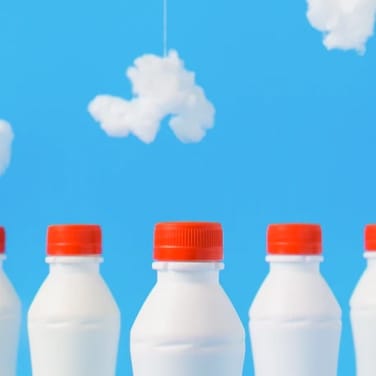 Three white milk bottle on cloudy background